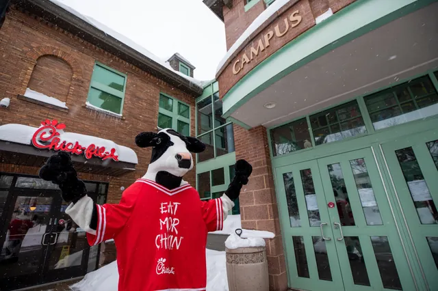 The Chick-fil-A cow in a red jersey outside the campus Chick-fil-A in the snow.