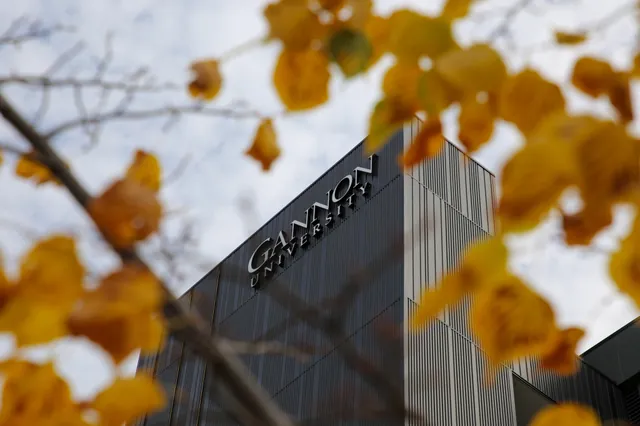 A dark Gannon University tower seen through yellow autumn leaves.