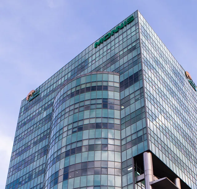 The glass Monnis Tower in Ulaanbaatar against a blue sky.