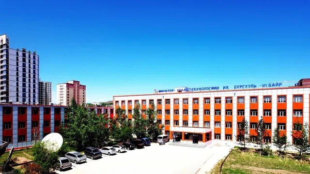 The orange-and-white Building VI of the Mongolian University of Science and Technology under a blue sky in Ulaanbaatar.